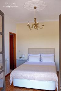 um quarto com uma cama grande e um lustre em Alecrim Rosmaninho Guest House em Pinhel