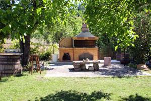 una chimenea de ladrillo en un patio con una mesa de picnic en Villa Karidia en Asprogerakata