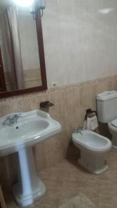 een badkamer met een wastafel, een toilet en een spiegel bij La guardia ll in A Guarda