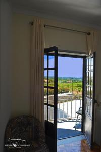 um quarto com uma porta de vidro deslizante e uma varanda em Alecrim Rosmaninho Guest House em Pinhel