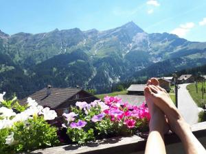 a person sitting on a ledge with their feet on flowers at Gasthaus Alpina in Tschappina