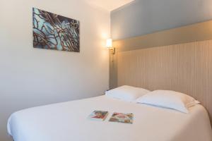 a bedroom with a white bed with a book on it at Pierre & Vacances Residence Les Rivages des Issambres in Les Issambres