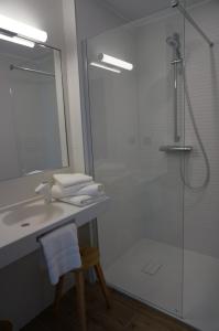een badkamer met een wastafel en een douche met een spiegel bij Hôtel Saint-Roch, The Originals Relais in Saint-Ybard
