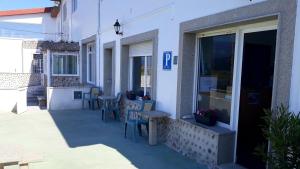 a building with tables and chairs on a patio at Hostal Balieiros Corrubedo in Corrubedo