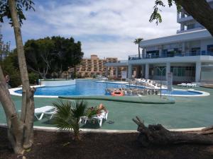 a swimming pool with a person sitting in a chair in front of a building at Studio Playa Paraiso Tenerife - ocean view and internet wifi optical fiber - for rent in Playa Paraiso