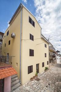 een groot wit gebouw met zwarte luiken bij Apartman Best in Novigrad Dalmatia