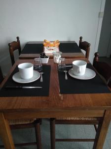 un tavolo di legno con due tazze e piatti sopra di Les Greniers De Blanche a Le Vivier-sur-Mer