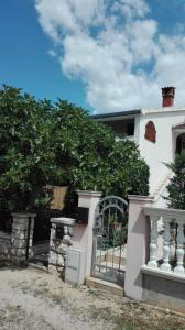 a white house with a gate and a tree at Apartmani Erceg in Jadrija