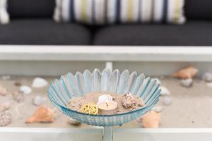 a table with a bowl of sand and a candle at Ferienhaus Strandperle in Bensersiel