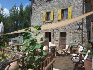 a patio with tables and chairs and a stone building at B&B Monte Splendore in Pietralunga