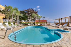 a pool with chaise lounge chairs and a resort at Canasvieiras Hotel in Florianópolis