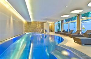 a swimming pool in a hotel with chairs and tables at Aktiv Hotel Schweizerhof Kitzbühel in Kitzbühel