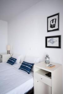 a white bed with blue pillows and a white table at Seven Books House in Carrazeda de Anciães