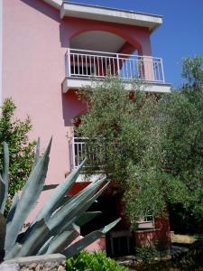 a pink building with a balcony and some plants at apartmani Vesna in Pinezici +4 photos