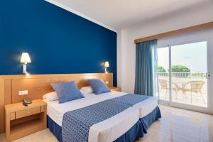 um quarto com uma cama com uma parede azul em Garden Playanatural - Adults Only em El Rompido