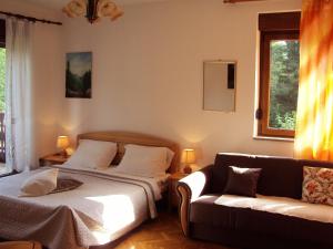 a bedroom with a bed and a couch at PLITVICE KONAK Daic in Plitvička Jezera