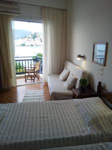 1 dormitorio con cama, sofá y balcón en Bissias Guest House, en Galatas