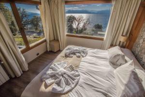 Cama en habitación con ventana grande en Bahia Paraiso Luxury Suites Boutique Hotel en San Carlos de Bariloche