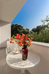 eine Vase mit Blumen auf einem Tisch auf einem Balkon in der Unterkunft Villa Milena in Brodarica