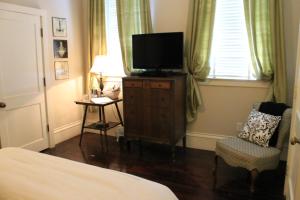 een slaapkamer met een bed, een tv en een stoel bij Grand Magnolia Ballroom & Suites in Pascagoula
