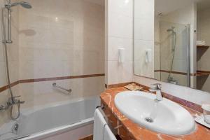 a bathroom with a sink and a tub and a mirror at Hotel Gran Rey in Valle Gran Rey