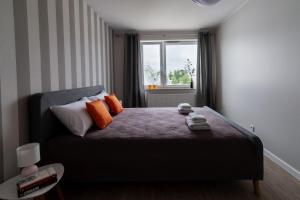 a bedroom with a bed with orange pillows and a window at Beżowe Love in Olsztyn