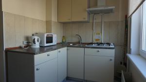 a small kitchen with white cabinets and a microwave at Sunny Ventspils 9 in Ventspils