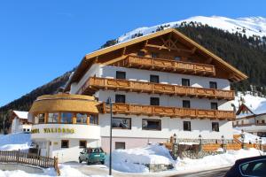 un grand bâtiment dans la neige devant une montagne dans l'établissement Hotel Valisera, à Galtür