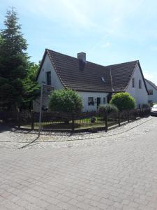 a white house with a black roof and a fence at Ferienwohnung Garz in Garz
