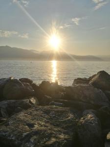 a sun setting over the water with rocks at Costaguta Apartment in Rapallo