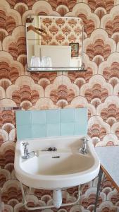 a bathroom with a sink and a mirror on a wall at Solheim Pensjonat in Røros