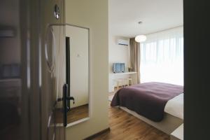 a bedroom with a bed and a door with a mirror at Camelia's cozy place in Baia Mare