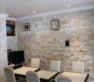 a room with two tables and chairs and a stone wall at Hôtel Aladin in Paris