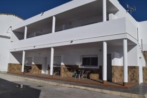 a white house with white columns and tables and chairs at Alojamientos Alma in Conil de la Frontera