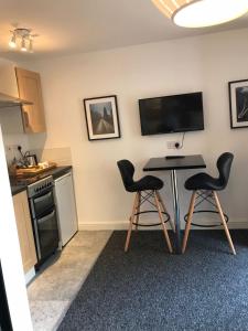 a kitchen with a table and two black chairs at Coleman Studios in Wolverhampton