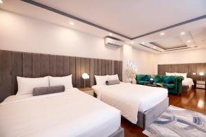een hotelkamer met 2 bedden en een bank bij Adora Hotel in Ho Chi Minh-stad