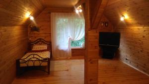 Habitación con cama y ventana en una cabaña de madera en Roguļi en Cērkste