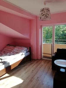 a bedroom with pink walls and a bed and a couch at Sis Dziwnowek in Dziwnówek
