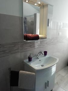 a white bathroom with a sink and a mirror at Apartments Hatic in Drenje