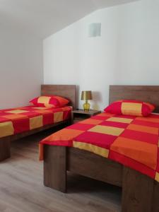 two beds in a room with red and orange at Apartments Hatic in Drenje