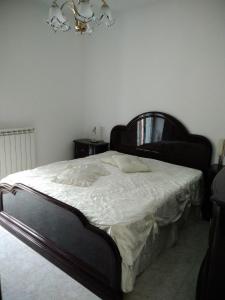 una camera da letto con un grande letto con lenzuola bianche e un lampadario a braccio di Casa Vacanza Chiesa Madre a Canicattì