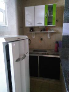 uma cozinha com um frigorífico branco e armários verdes em Kitnet em Guarapari em Guarapari