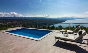 a swimming pool on a patio with a view of the water at Villa vista sul Quarnero in Matulji