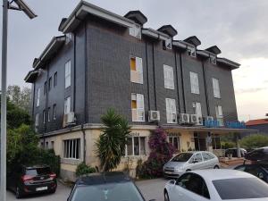 un gran edificio con coches estacionados frente a él en Hotel Camargo, en Igollo