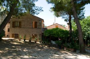 ein Haus mit Bäumen und Topfpflanzen davor in der Unterkunft B&B La Cappellania in Montegiorgio