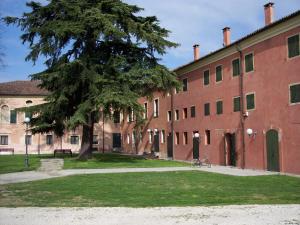 un grand bâtiment en briques rouges avec un arbre en face de lui dans l'établissement Hotel La Corte, à Correzzola