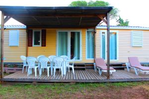 una terraza con mesa y sillas y una casa en Mobil home florida - camping les cigales - 4 étoiles, en Le Muy