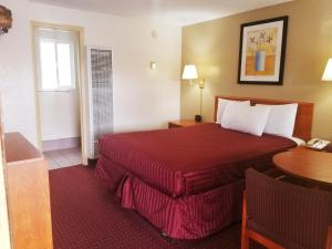 um quarto de hotel com uma cama vermelha e uma mesa em Americas Best Value Inn-Williams/Grand Canyon em Williams
