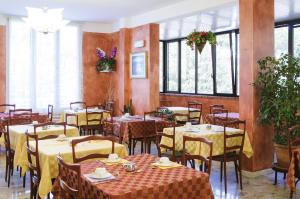 un comedor con mesas, sillas y ventanas en Hotel Edelweiss, en Cervia