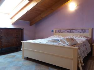 - une chambre avec un lit blanc et une tête de lit en bois dans l'établissement Casa Vacanze I Boidi, à Nizza Monferrato